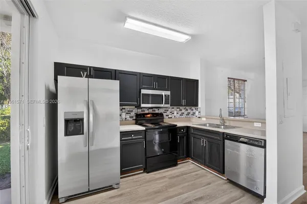 a kitchen with a sink a refrigerator a stove and wooden floors