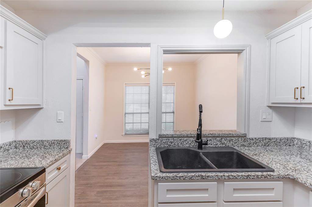 12680 Hillcrest Road, Unit 4101 Dallas, TX 75230 - Photo 11 of 37 Kitchen featuring white cabinetry with bronze-tone hardware, speckled countertops, a dark double-basin sink with a matte black faucet, and wood-finish flooring