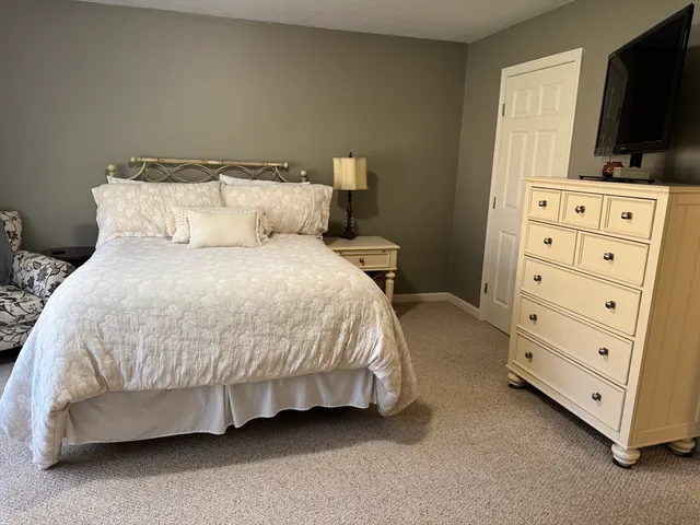 a bedroom with a bed and a flat tv screen on dresser