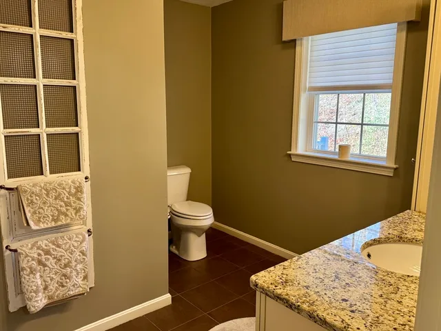 a bathroom with a granite countertop sink and a toilet