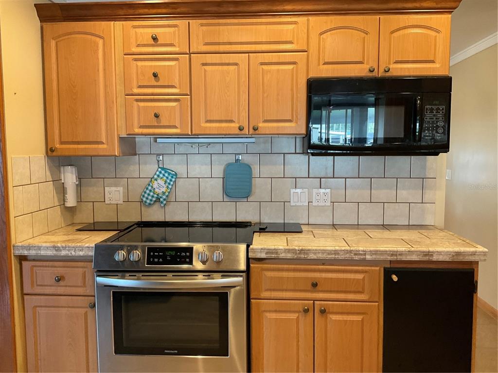 1558 Chobee Street Okeechobee, FL 34974 - Photo 44 of 63 a kitchen with granite countertop a stove top oven microwave and cabinets