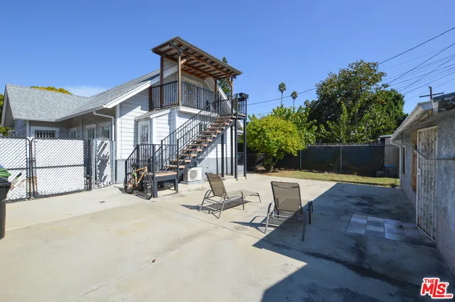 a view of a patio with a table and chairs under an umbrella with wooden fence