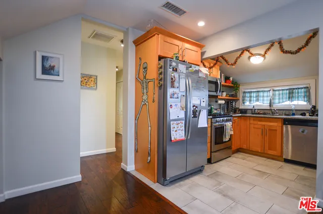 a kitchen with stainless steel appliances granite countertop a refrigerator and a wooden cabinets