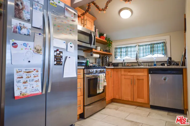 a kitchen with granite countertop a refrigerator and a stove top oven