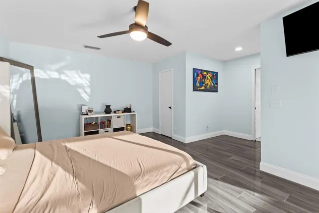 a spacious bedroom with a bed and a flat screen tv