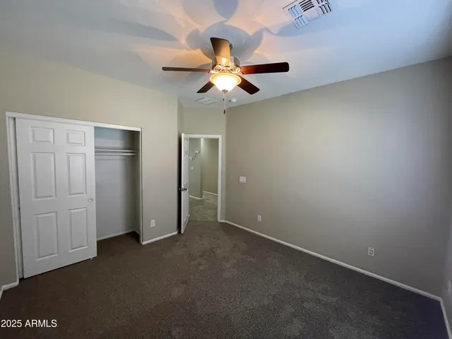 an empty room with closet and a chandelier fan