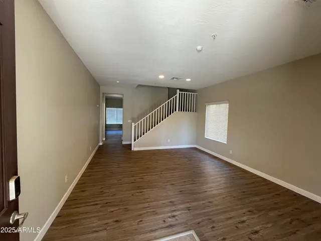 a view of an empty room with wooden floor and stairs