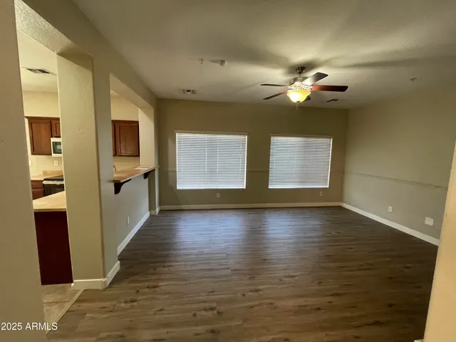 a view of an empty room with a window and wooden floor