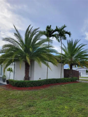 a front view of house with yard and palm tree