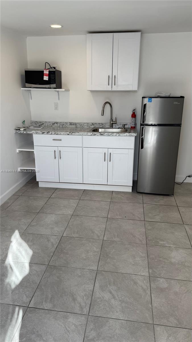 12764 Southwest 46th Lane, Unit 12764 Miami, FL 33175 - Photo 3 of 13 a kitchen with a sink a refrigerator and cabinets