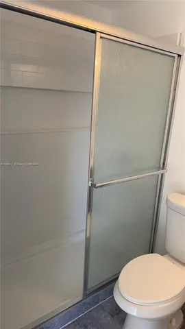 a white toilet sitting next to a shower