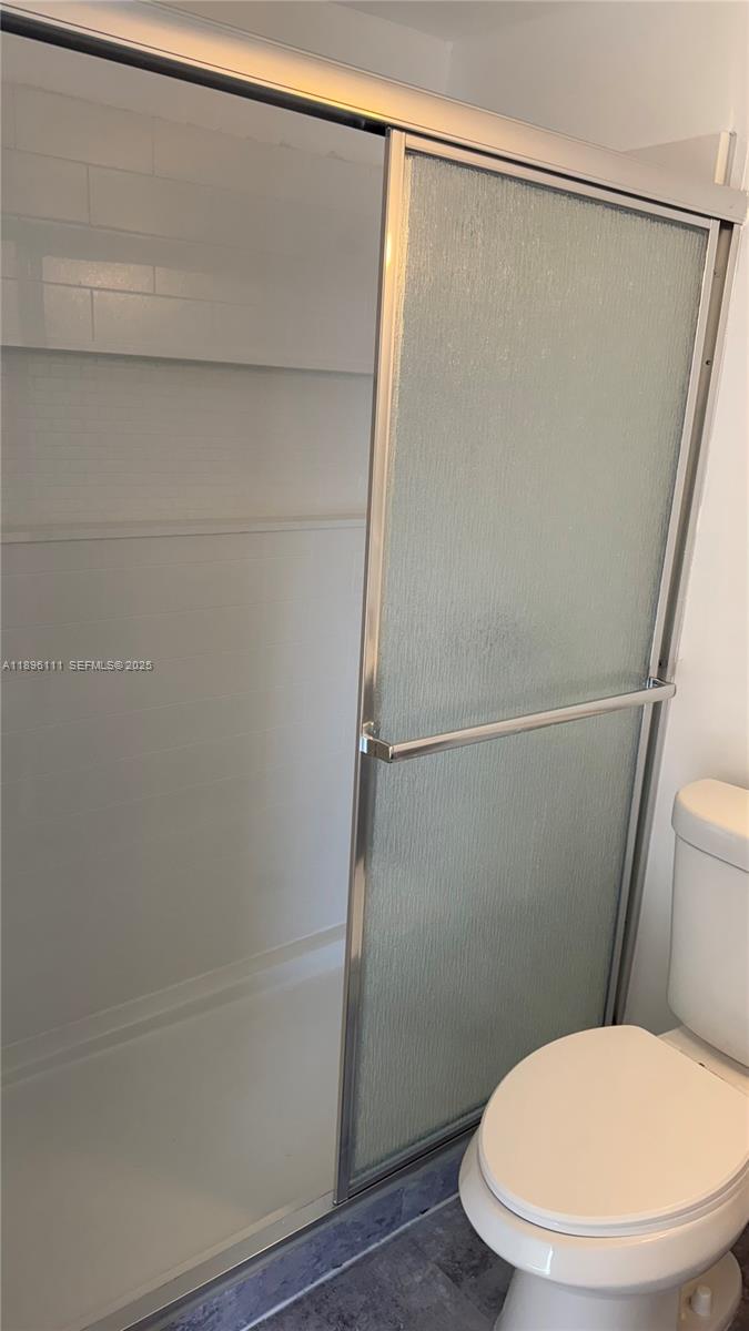 12764 Southwest 46th Lane, Unit 12764 Miami, FL 33175 - Photo 6 of 13 a white toilet sitting next to a shower
