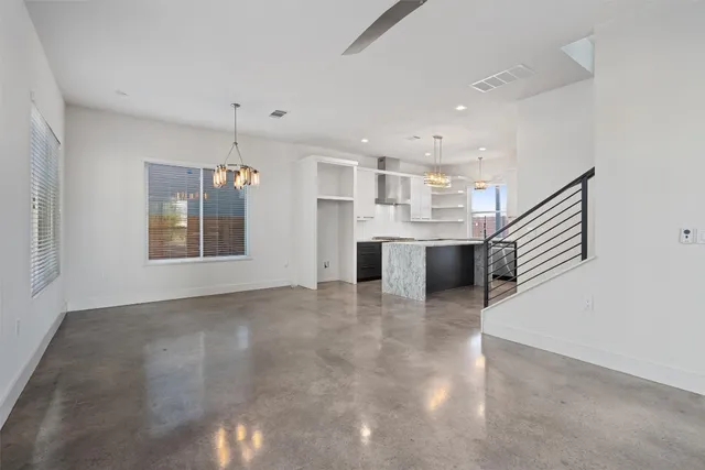 an empty room with wooden floor and kitchen view
