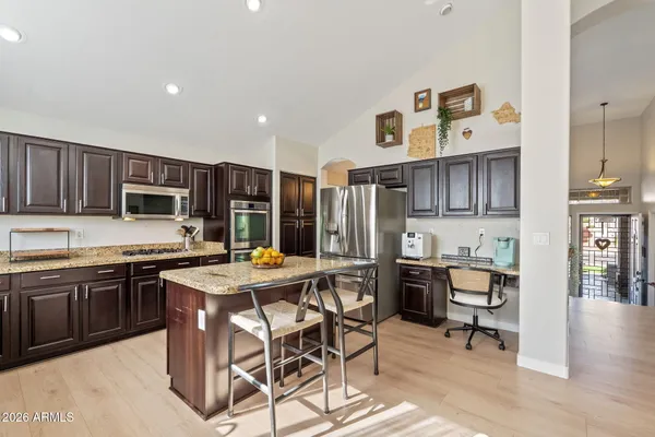 a kitchen with stainless steel appliances granite countertop a table chairs sink and cabinets