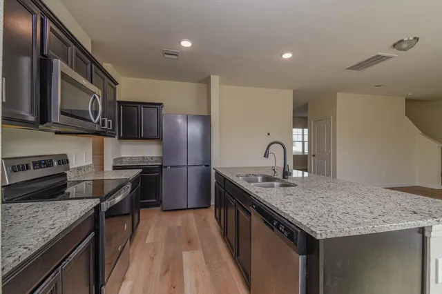 a kitchen with stainless steel appliances granite countertop a kitchen island a stove a refrigerator and a sink