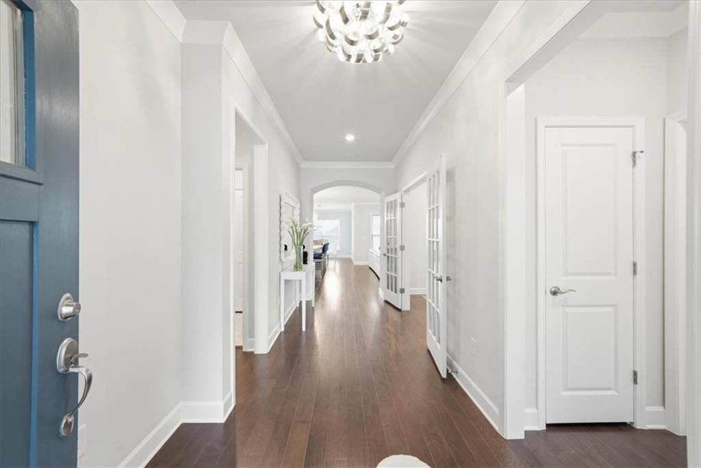 2457 Naples Street Hoschton, GA 30548 - Photo 3 of 41 a view of a hallway with wooden floor and a chandelier