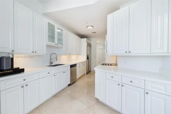a large white kitchen with granite countertop white cabinets and stainless steel appliances