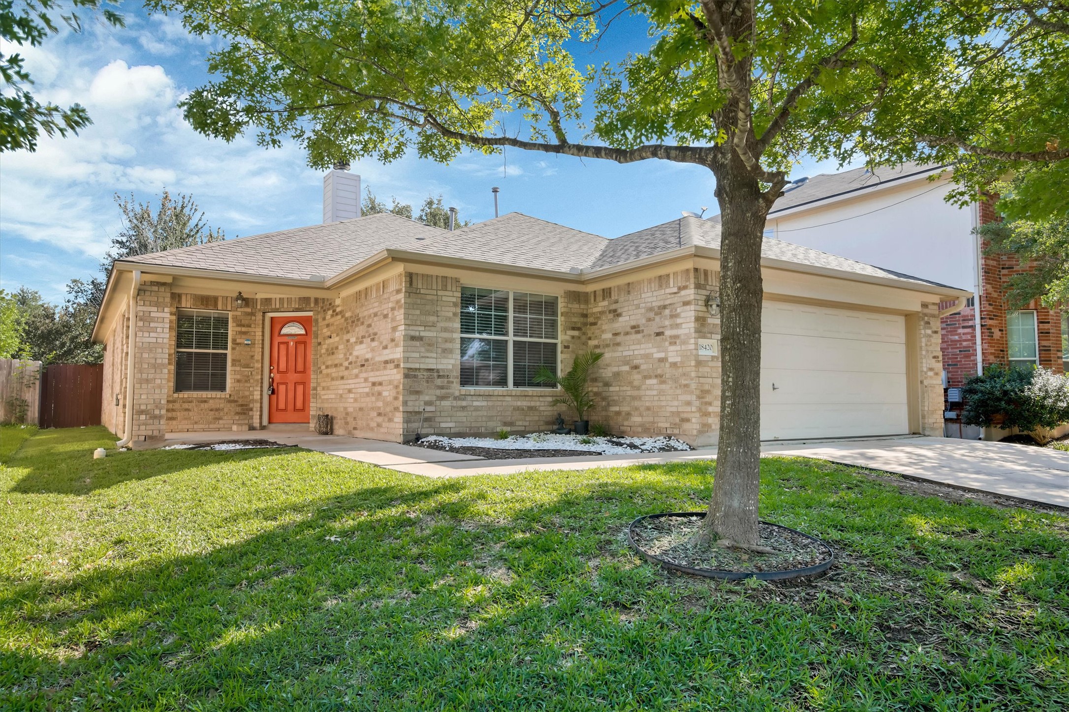 18420 Masi Loop Pflugerville, TX 78660 - Photo 3 of 33 Single-story brick exterior with an attached two-car garage, a covered front porch, and a bright red entry door