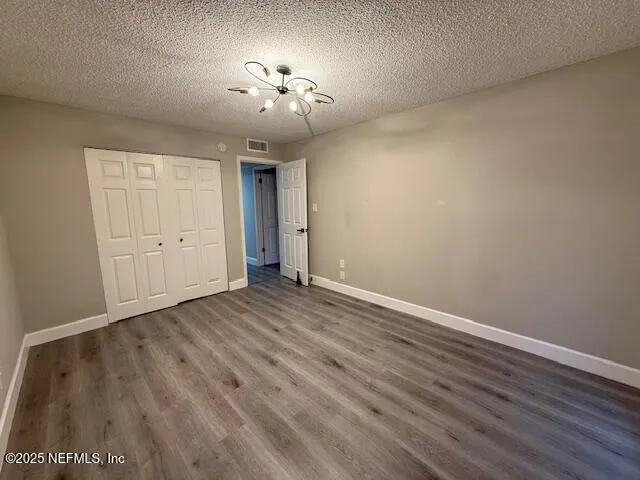 an empty room with wooden floor and chandelier