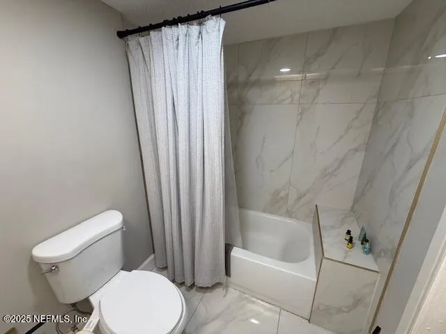 a white toilet sitting next to a bath tub