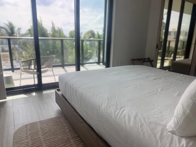 a large white bed sitting in a bedroom next to a large window