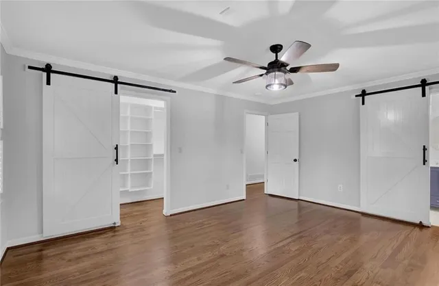 a view of a livingroom with wooden floor a ceiling fan and windows