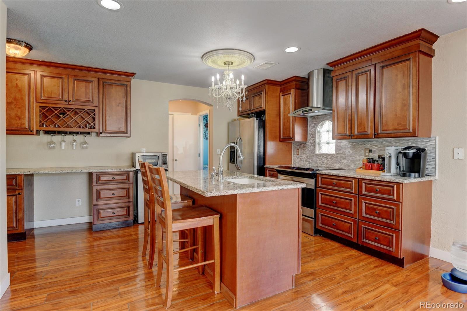 5555 Perth Court Denver, CO 80249 - Photo 12 of 31 a kitchen with stainless steel appliances granite countertop a stove a sink dishwasher and a refrigerator with wooden floor