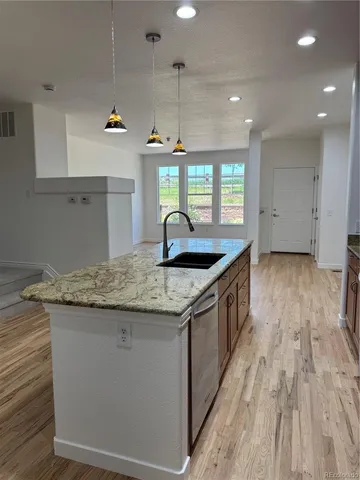 a kitchen with granite countertop a sink and a wooden floor