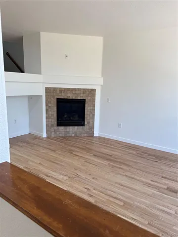 a view of empty room with wooden floor and fireplace