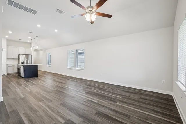 a view of kitchen and empty room with wooden floor
