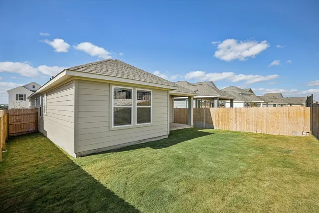a view of a yard in front of a house with wooden fence