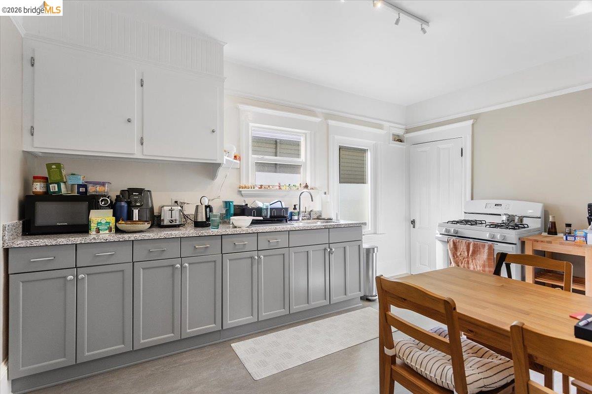 3110 California Street Berkeley, CA 94703 - Photo 17 of 41 Dual tone kitchen with two tone cabinetry, white gas stove, black microwave, light stone counters, and dark wood-style floors
