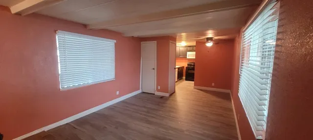a view of an empty room with wooden floor and a window