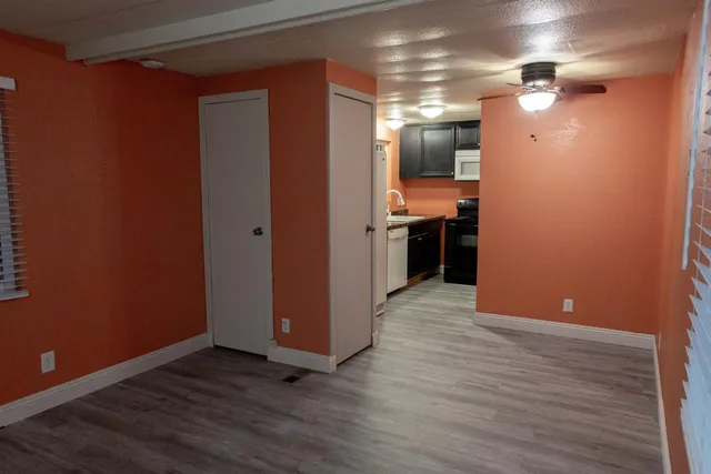 a view of a hallway with wooden floor and a kitchen