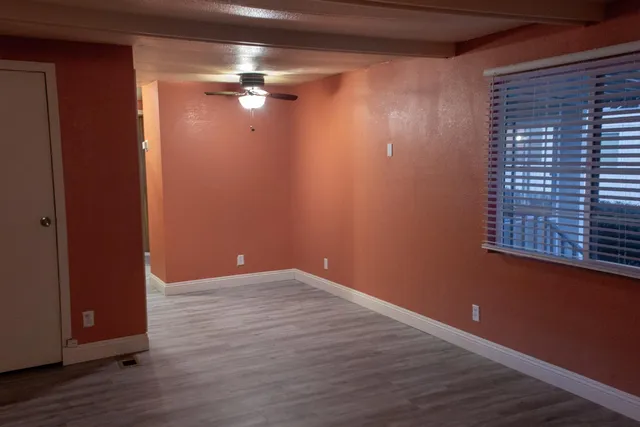 a view of an empty room with wooden floor and a window