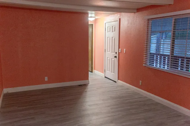 a view of an empty room with wooden floor and a window