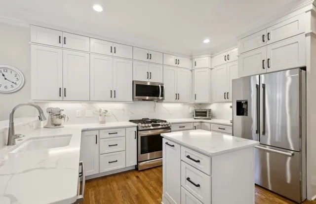 a kitchen with white cabinets sink and stainless steel appliances