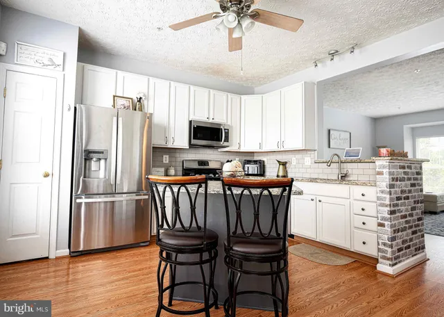 a kitchen with stainless steel appliances a refrigerator a stove a sink dishwasher a dining table and chairs with wooden floor