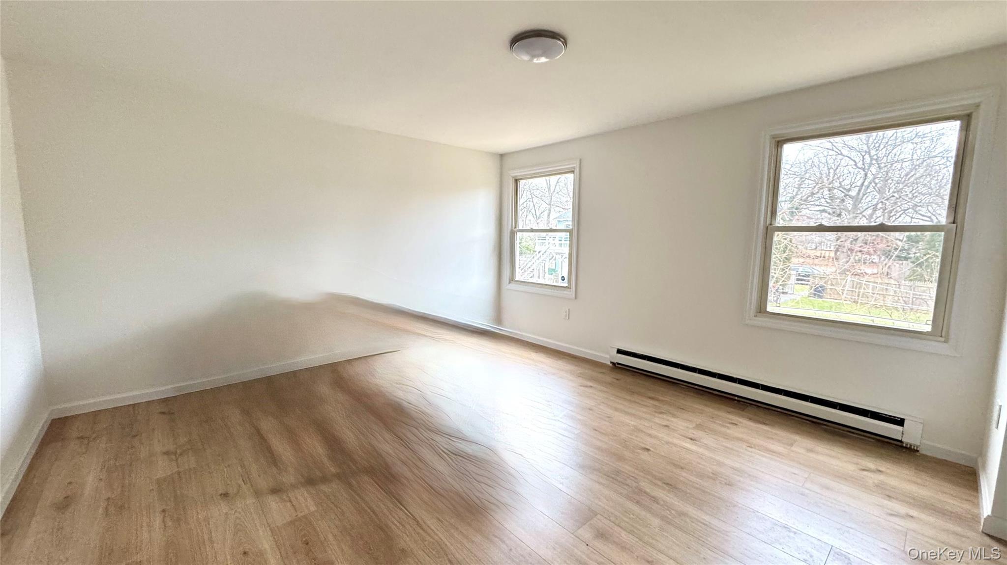 61 Gould Road Centereach, NY 11720 - Photo 8 of 22 an empty room with wooden floor and windows