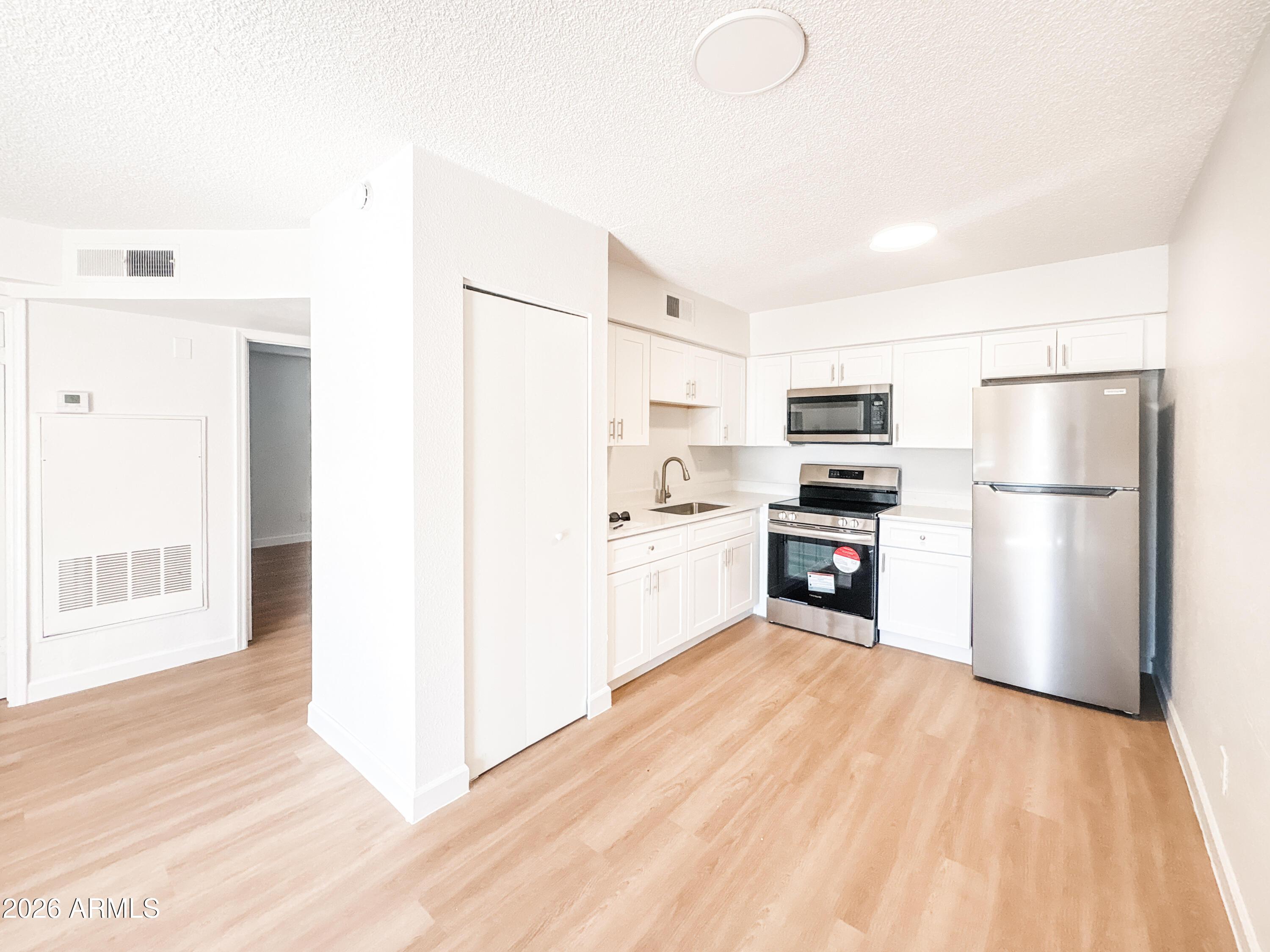 2615 East Greenway Road, Unit 21 Phoenix, AZ 85032 - Photo 11 of 19 a kitchen with white cabinets and stainless steel appliances