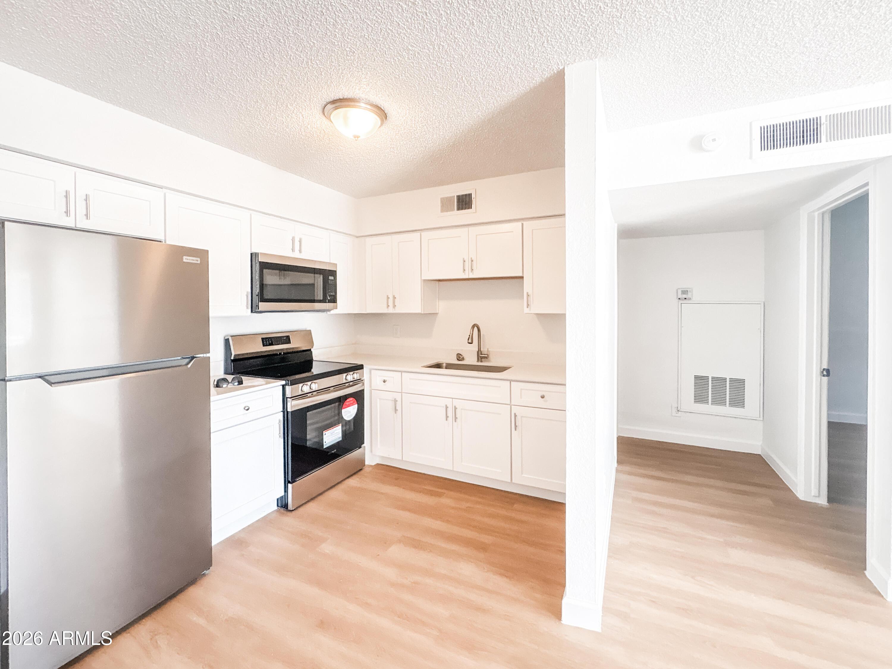 2615 East Greenway Road, Unit 21 Phoenix, AZ 85032 - Photo 12 of 19 a kitchen with a refrigerator a stove top oven a sink and dishwasher