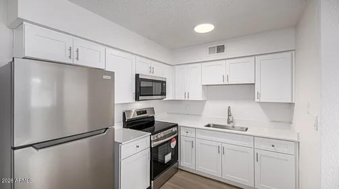 2615 East Greenway Road, Unit 21 Phoenix, AZ 85032 - Photo 2 of 19 a kitchen with stainless steel appliances white cabinets and a refrigerator