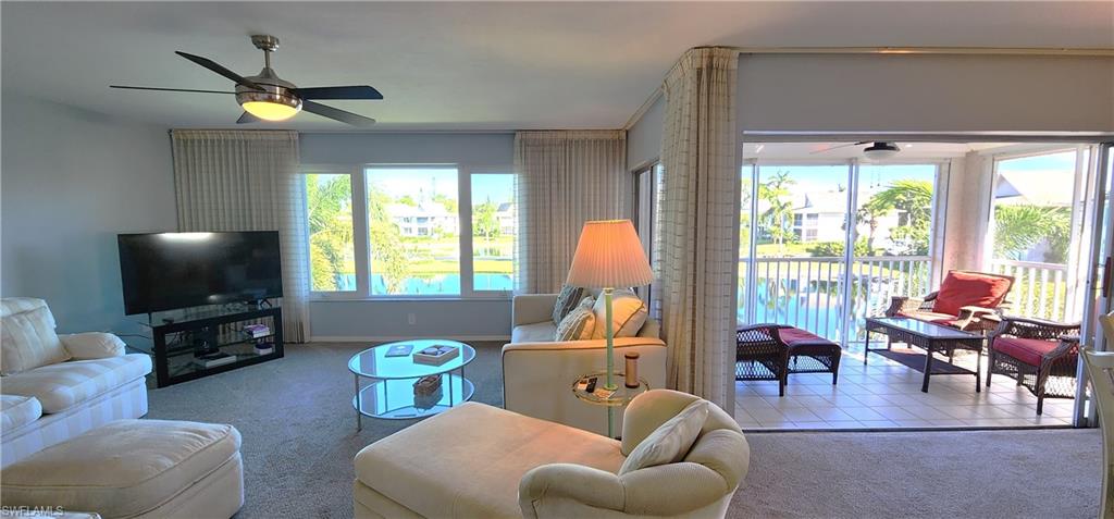 75 Georgetown Boulevard, Unit 75 Naples, FL 34112 - Photo 4 of 28 Living room featuring light carpet, ceiling fan, and a healthy amount of sunlight