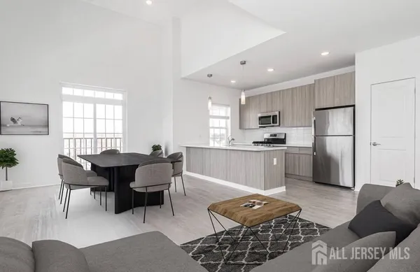 a open kitchen with stainless steel appliances kitchen island granite countertop a dining table chairs and a refrigerator