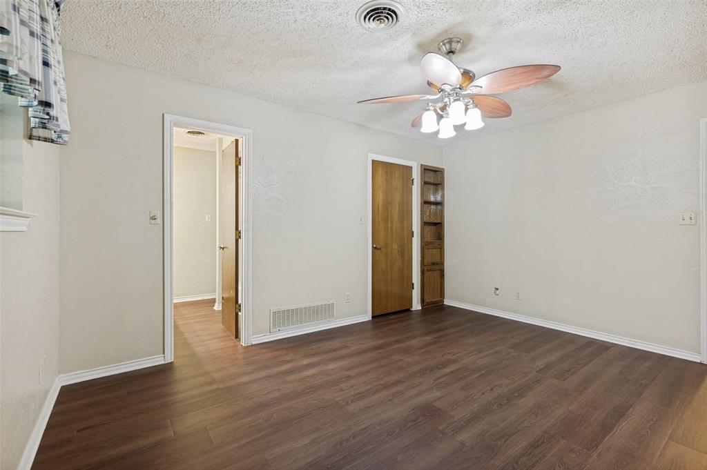 508 South Pedigo Street Pilot Point, TX 76258 - Photo 13 of 26 Spacious bedroom featuring wood-finish flooring, light-toned walls, and a ceiling fan with integrated lighting