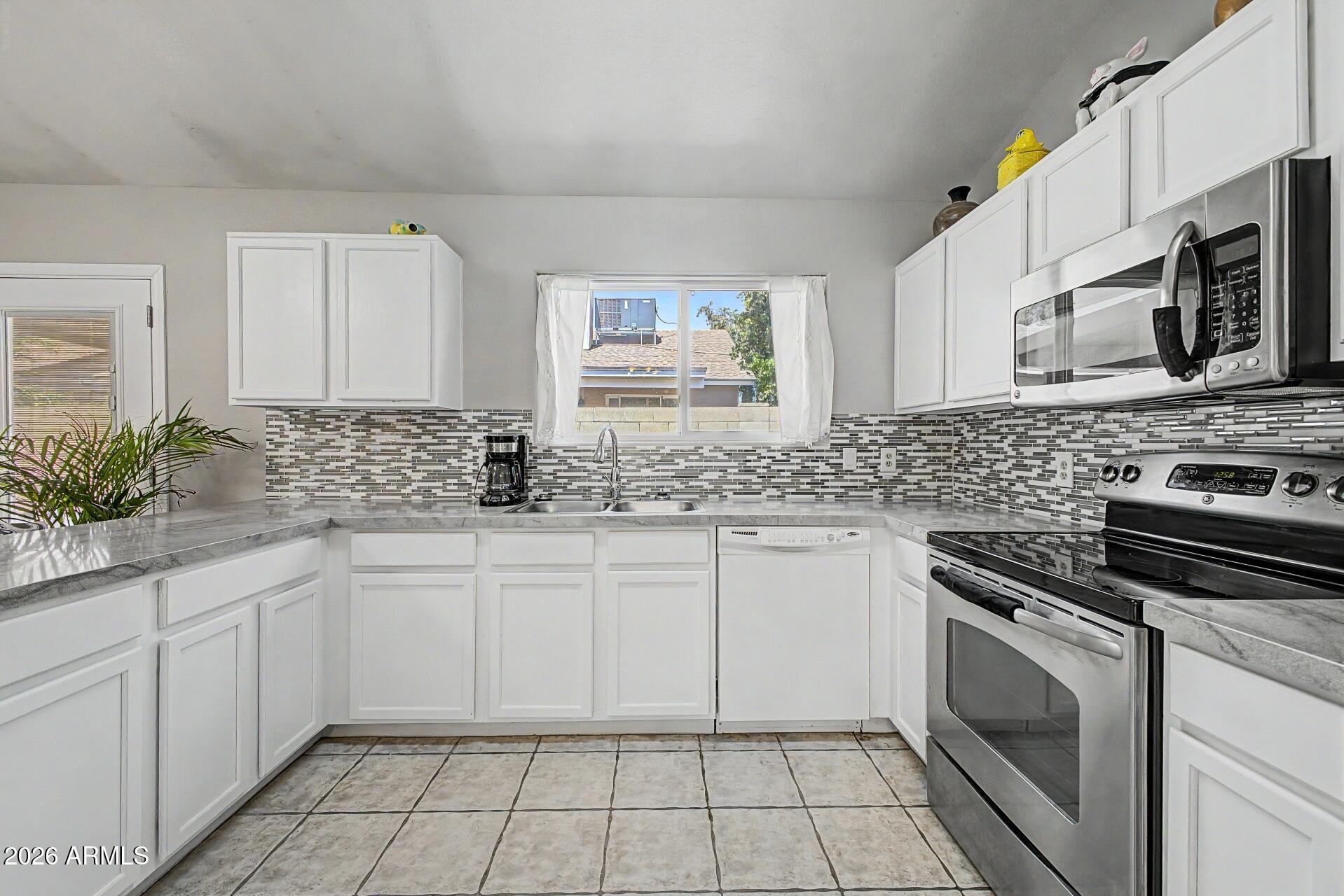 6335 East Brown Road, Unit 1144 Mesa, AZ 85205 - Photo 11 of 28 a kitchen with stainless steel appliances granite countertop a sink stove and microwave