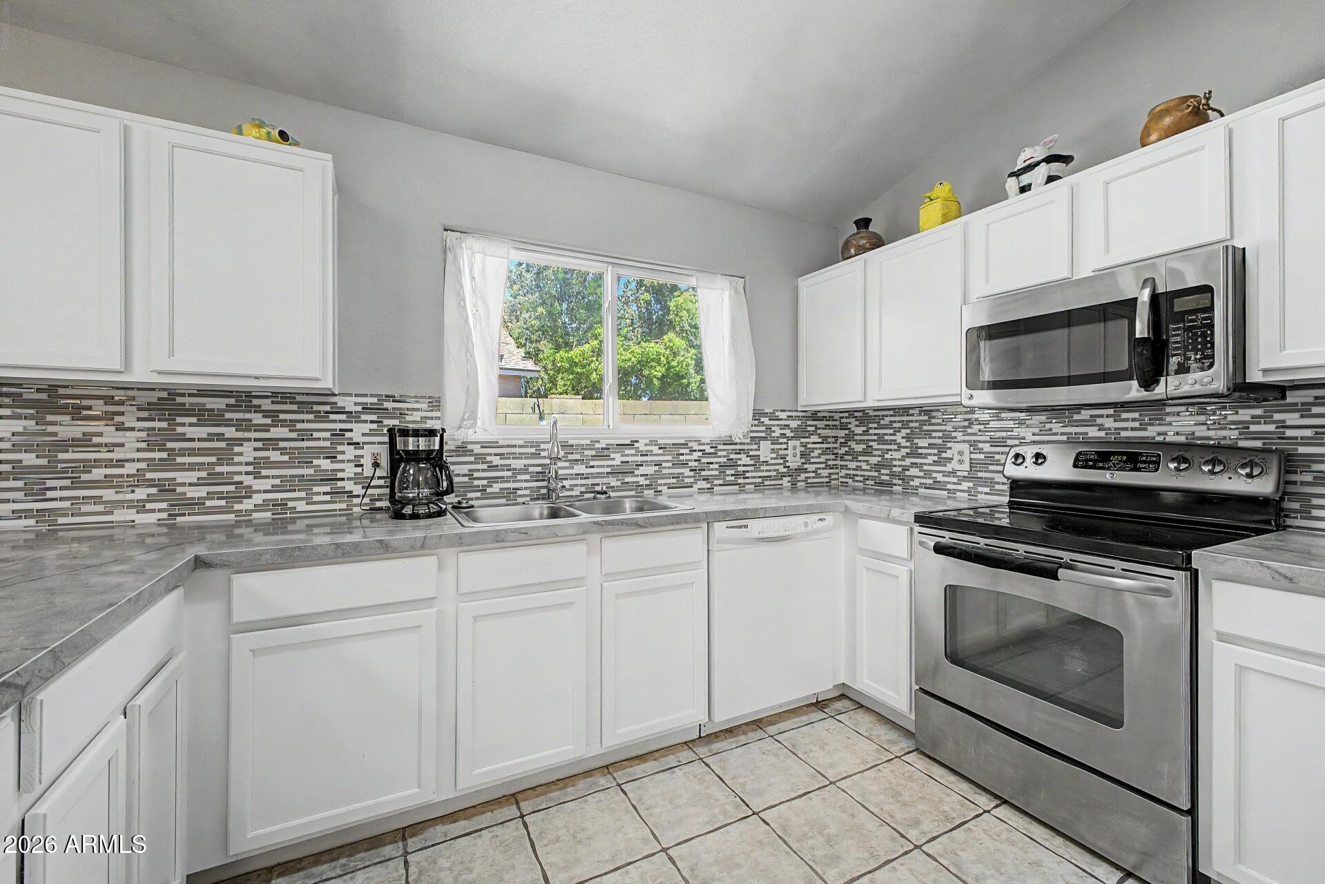 6335 East Brown Road, Unit 1144 Mesa, AZ 85205 - Photo 12 of 28 a kitchen with granite countertop white cabinets stainless steel appliances and a sink