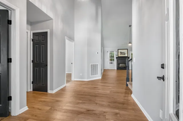 a view of a hallway with wooden floor and a bathroom