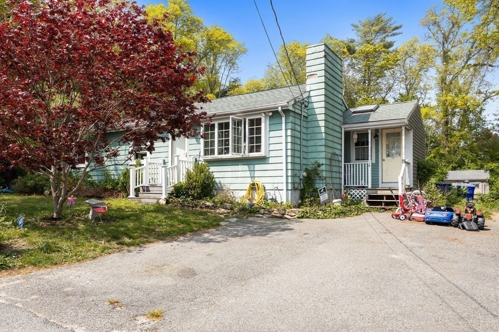 a view of a house with a small yard and a large tree