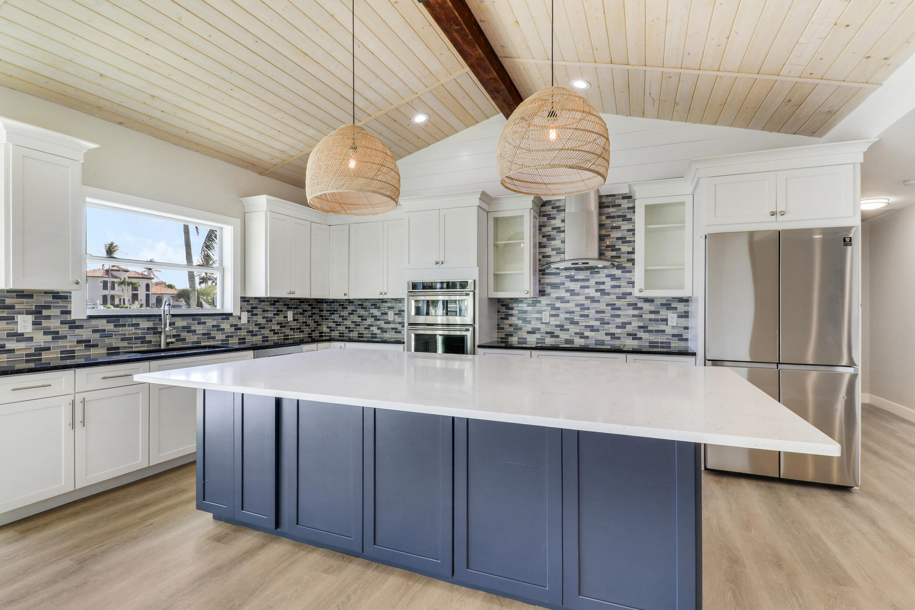 9195 Southeast Cove Point Street Jupiter, FL 33469 - Photo 29 of 80 a kitchen with stainless steel appliances a refrigerator a sink dishwasher and white cabinets with wooden floor